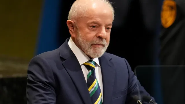 Documentos oficiais e selos de governo sobre uma mesa, com bandeira americana ao fundo, simbolizando relações diplomáticas