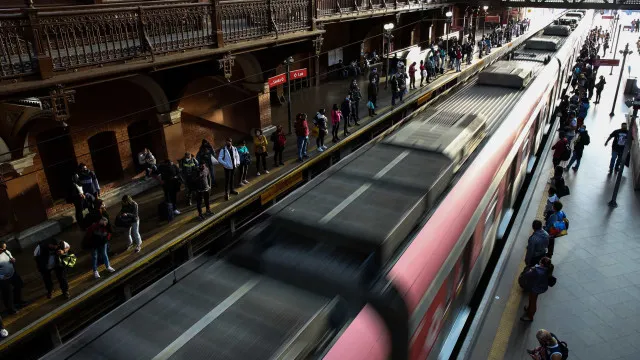 Plataforma de estação de metrô vazia à noite, com uma mala solitária em um banco.