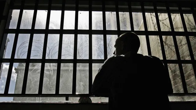 Ilustração de muro de presídio com arame farpado, torre de vigilância ao fundo e estruturas de segurança reforçadas